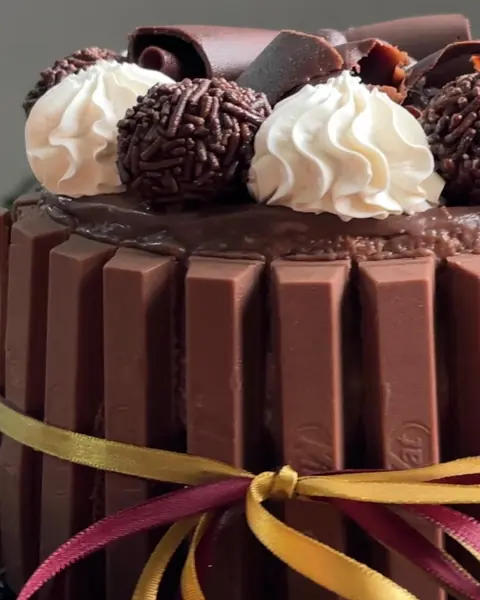 Bolo de chocolate com brigadeiros, chantilly e fitas
