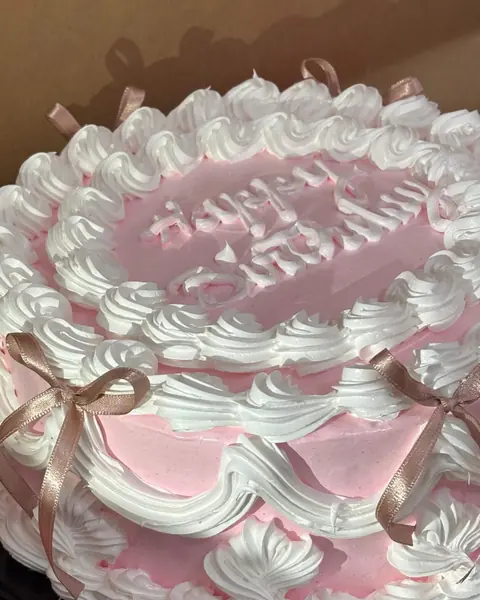 Bolo decorado com chantilly rosa e branco e laços de fita