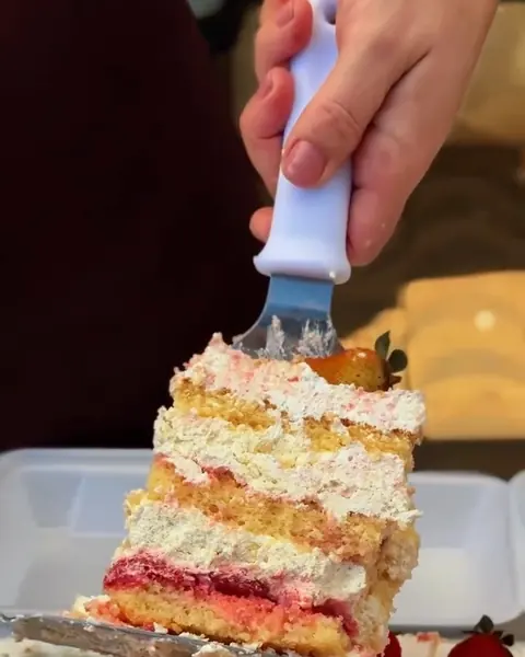 Fatia de bolo de ninho com morango sendo servida