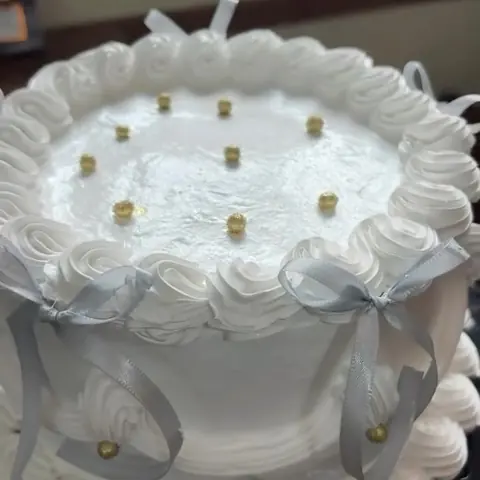 Bolo branco decorado com chantilly e laços prateados