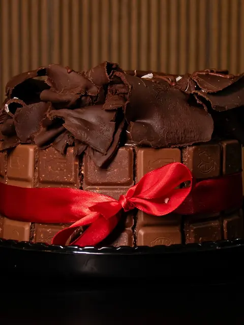 Bolo de chocolate com raspas e laço vermelho