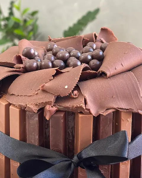 Bolo de chocolate com placas de chocolate, bolinhas crocantes e laço de fita