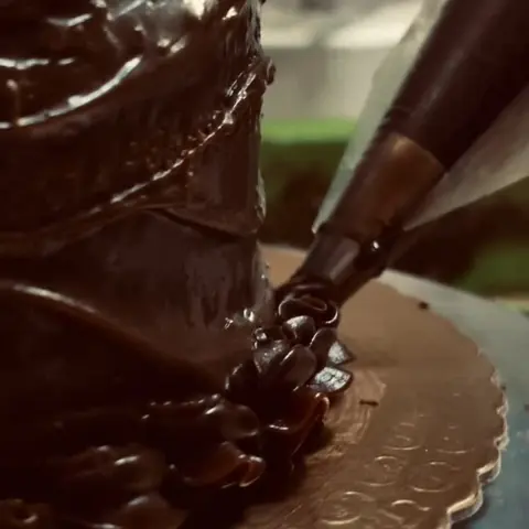 Ganache de chocolate sendo aplicada no bolo