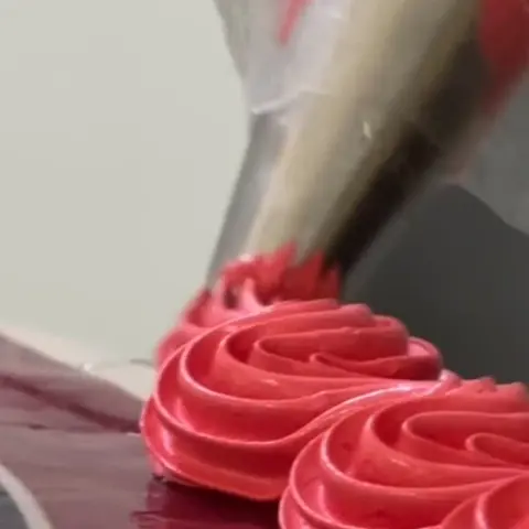 Confeiteira decorando bolo com bico de confeitar